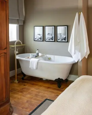 a white tub in a bathroom with three pictures on the wall at The Belmont in Franschhoek
