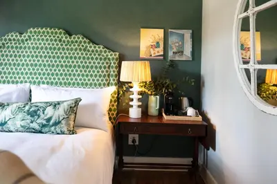a bedroom with a bed and a table with a lamp at The Belmont in Franschhoek