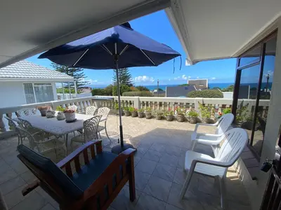 a patio with a table and chairs and an umbrella at Somstuis in Hermanus