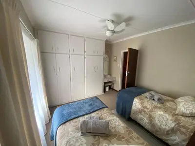 a bedroom with two beds and a ceiling fan at Somstuis in Hermanus