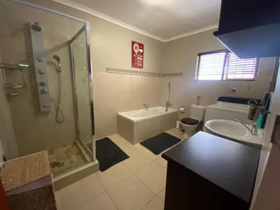 a bathroom with a shower and a tub and a sink at Somstuis in Hermanus
