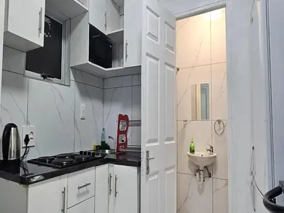 a white kitchen with a stove and a sink at Goshen Lodge Fitzroy in Cape Town