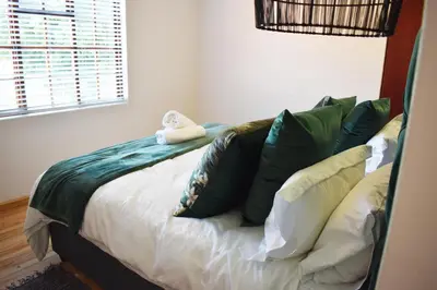 a bedroom with a bed with green and white pillows at The Botanical House in Somerset West