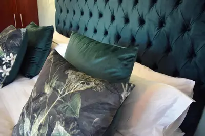 a bed with two green pillows on it at The Botanical House in Somerset West