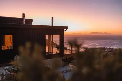a house with the sunset in the background at Klein-Hangklip in Rooiels