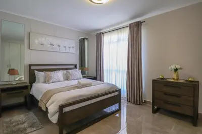 a bedroom with a bed and a dresser and a window at 405 Portofino Eyrie Holiday Apartments in Cape Town