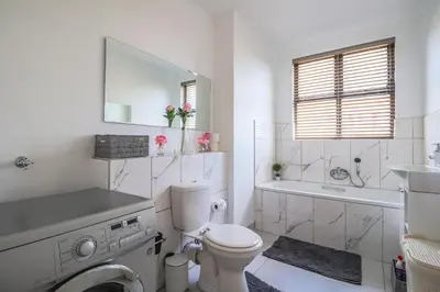 a white bathroom with a toilet and a tub and a sink at 102 Palma Eyrie Holiday Apartments in Cape Town