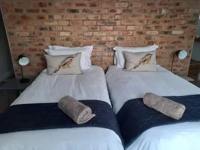 two beds with pillows sitting next to a brick wall at Marine View in Hermanus