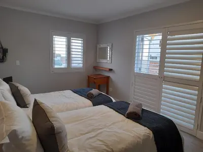a bedroom with two beds and a window with blinds at Marine View in Hermanus