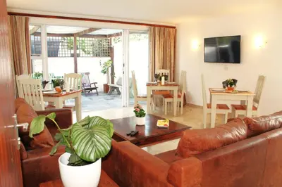 a living room with a leather couch and a table at 7th Wonder Beach Guest House in Cape Town
