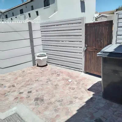 a patio with a fence and a trash can at Tia Maria cottage in Cape Town