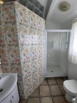 a bathroom with a shower and a toilet and a sink at Fynbosrus on Grotto in Hermanus