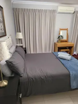 a bedroom with a bed and a table with a mirror at Fynbosrus on Grotto in Hermanus