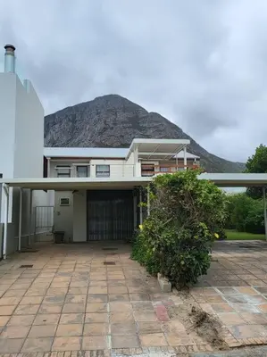 a large house with a mountain in the background at Fynbosrus on Grotto in Hermanus