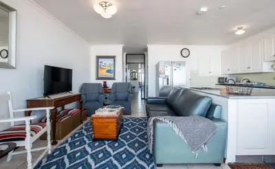 a living room with a couch and a kitchen at Strand Apartment only 30 meters from beach in Cape Town