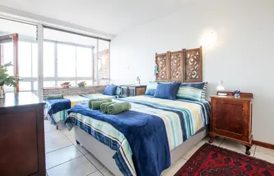 a bedroom with two beds with blue and white sheets at Strand Apartment only 30 meters from beach in Cape Town