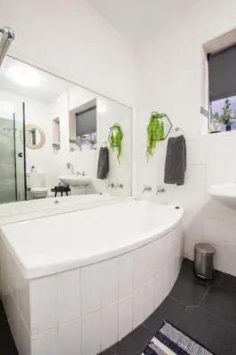 a white bathroom with a tub and a sink at Strand Apartment only 30 meters from beach in Cape Town