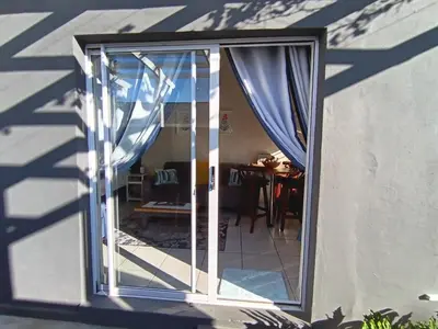 an open glass door with curtains in a room at Dalau on Main in Paarl