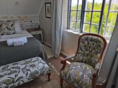 a bedroom with a bed and a chair and a window at Vermont Lofts in Hermanus