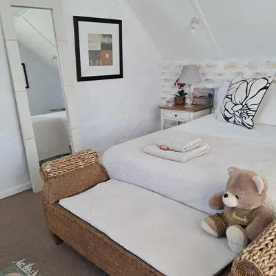 a teddy bear sitting on a bed in a bedroom at Vermont Lofts in Hermanus