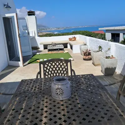 a patio with a table and chairs on a balcony at Vermont Lofts in Hermanus