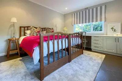a bedroom with a wooden bed with a red blanket at Ivy House - Super Spacious Spot- Somerset West in Somerset West