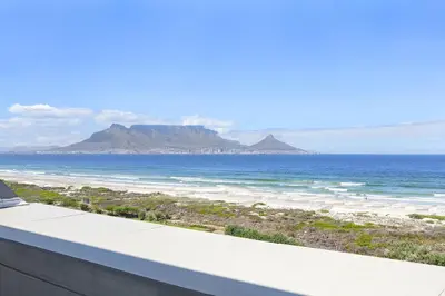 a view of the ocean from the balcony of a house at Dolphin Beach H301 by Host Agents in Bloubergstrand