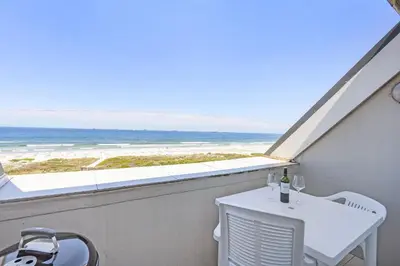 a balcony with a table and a view of the ocean at Dolphin Beach H301 by Host Agents in Bloubergstrand