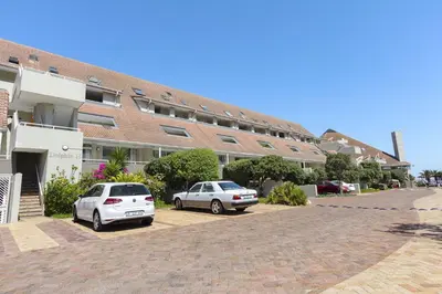 two cars parked in a parking lot in front of a building at Dolphin Beach H301 by Host Agents in Bloubergstrand
