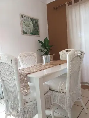 a white dining room table with white wicker chairs at Santika Getaway Cottage Stellenbosch in Stellenbosch