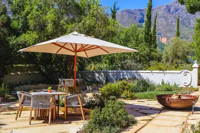 a table and chairs under an umbrella on a patio at La Villa in Franschhoek