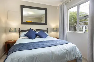 a bedroom with a bed with blue pillows and a mirror at Tuis en Tevrede - 1 Bedroom Flat in Hermanus