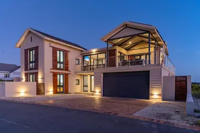a large house with a garage at dusk at Hermanus Beach House at CShine in Hermanus