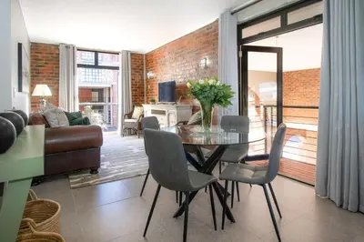 a living room with a glass table and chairs at The Xrossing - free parking in Stellenbosch