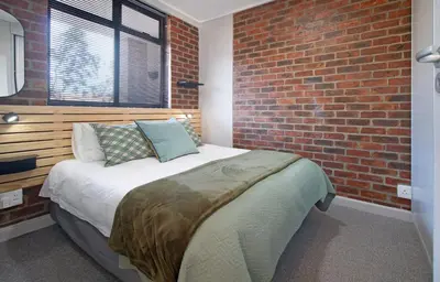 a bedroom with a bed with a brick wall at The Xrossing - free parking in Stellenbosch
