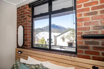 a brick wall with a window with a mountain view at The Xrossing - free parking in Stellenbosch