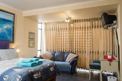 a bedroom with a bed and a couch and a tv at 5 Lantra in Strand