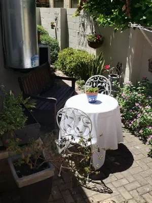 a table and chairs in a garden with a vase on it at Hermanus Sea view room in Hermanus