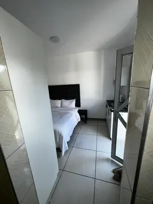 a bedroom with a white bed and a mirror at Beatrice Guesthouse in Cape Town