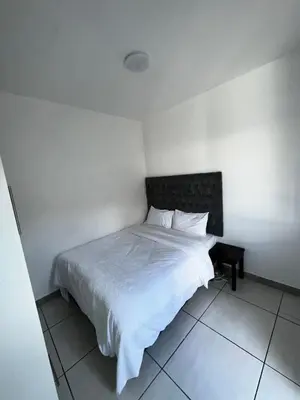 a bedroom with a white bed with a black headboard at Beatrice Guesthouse in Cape Town