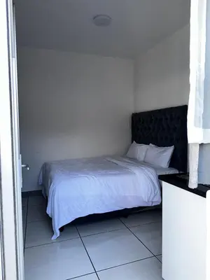 a bedroom with a white bed with a black headboard at Beatrice Guesthouse in Cape Town