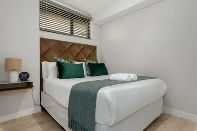 a bedroom with a large white bed with green pillows at Burmeister on Park 007 in Cape Town