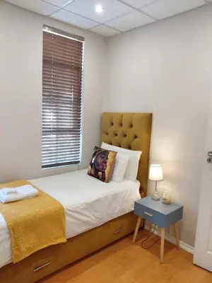a bedroom with a bed and a table with a lamp at The Skinny Expat - Paarl - Self Catering Apartment in Paarl
