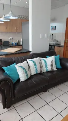 a black leather couch with blue and white pillows on it at The Tipsy Expat - Paarl - Self Catering Apartment in Paarl