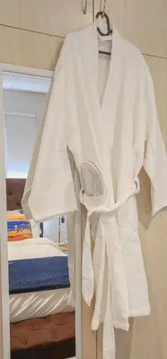 a white robe hanging on a wall next to a bed at The Tipsy Expat - Paarl - Self Catering Apartment in Paarl