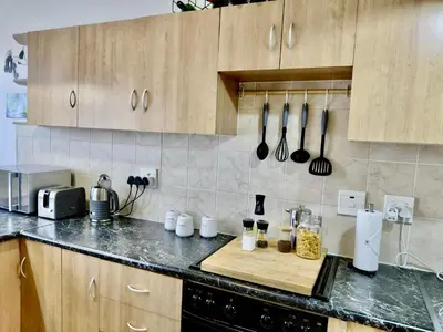 a kitchen with wooden cabinets and a wooden cutting board at The Tipsy Expat - Paarl - Self Catering Apartment in Paarl
