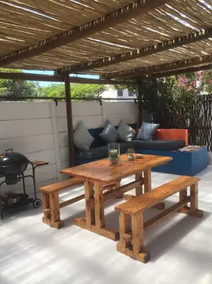 a picnic table and benches under a wooden pergola at A spacious Haven near Bloubergstrand beach in Cape Town