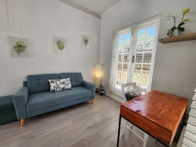 a living room with a blue couch and a table at A spacious Haven near Bloubergstrand beach in Cape Town