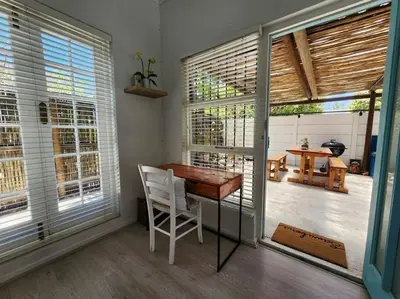 a room with a table and a chair and windows at A spacious Haven near Bloubergstrand beach in Cape Town
