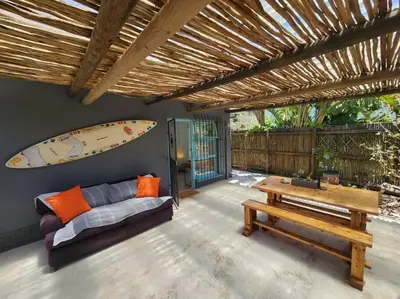 a living room with a couch and a surfboard on the wall at A spacious Haven near Bloubergstrand beach in Cape Town